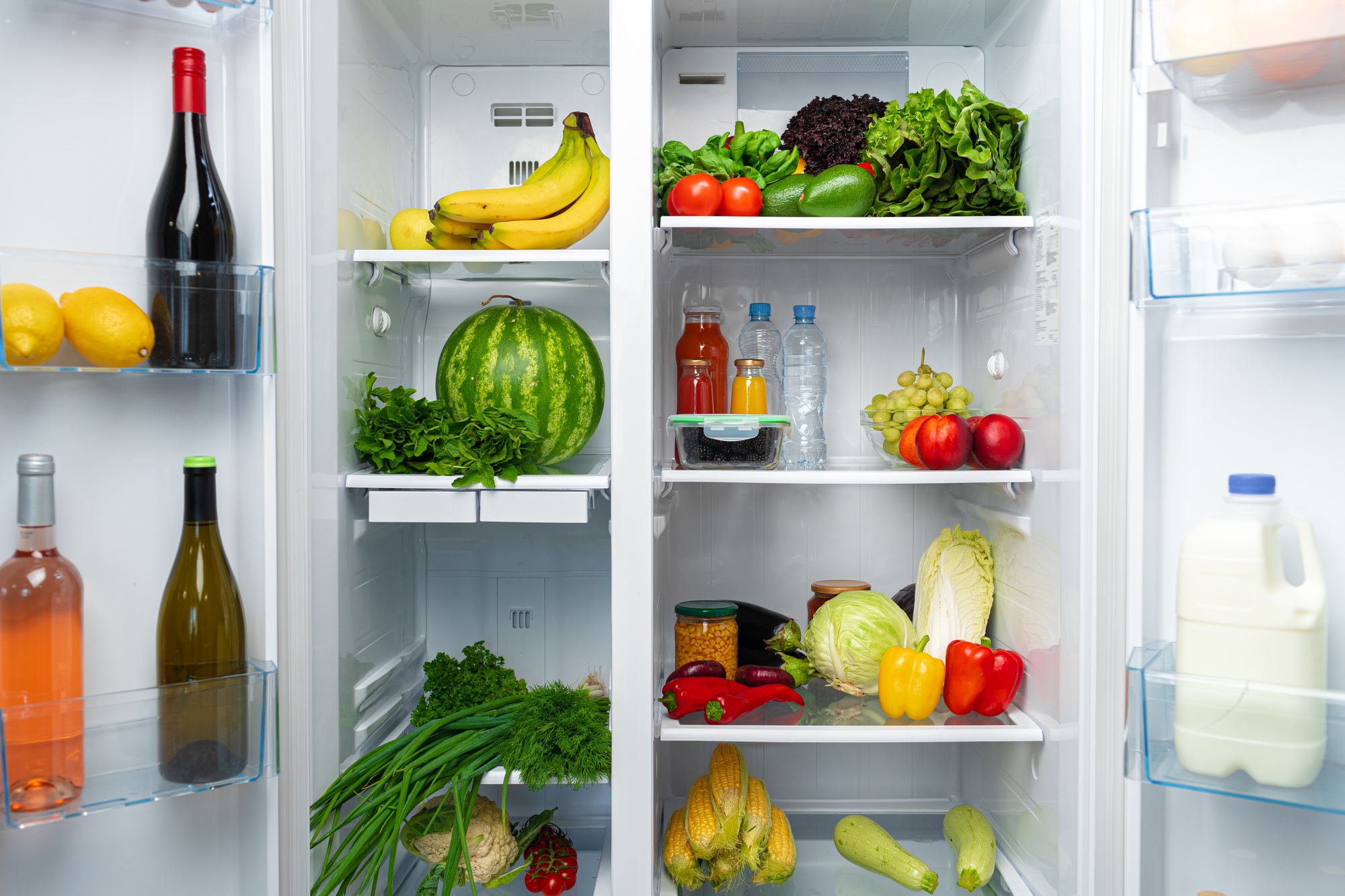 Open fridge full of fruits, vegetables and drinks