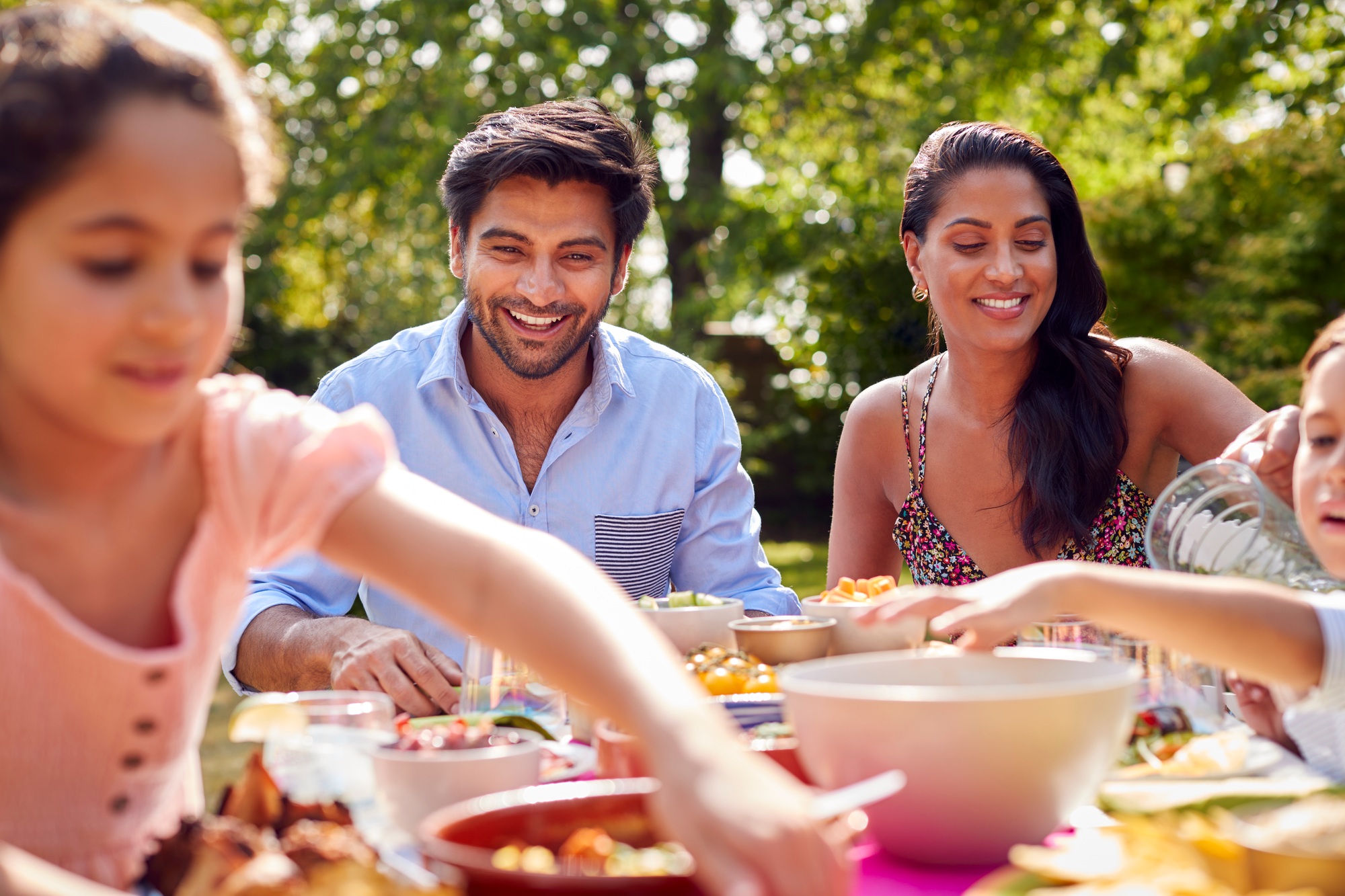 Family Eating Outdoor Meal In Garden At Home Together